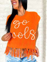 Load image into Gallery viewer, Close up view of a woman wearing Queen of Sparkles orange fringe sweater vest with 'go vols' text on the front, paired with denim shorts.