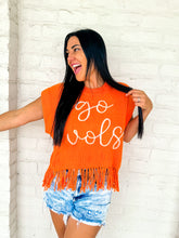 Load image into Gallery viewer, A woman wearing Queen of Sparkles orange fringe sweater vest with 'go vols' text on the front, paired with denim shorts.