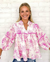 Load image into Gallery viewer, Woman wearing a pink floral blouse against a white brick wall