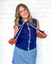Load image into Gallery viewer, Woman wearing a blue sleeveless top with decorative trim against a white brick wall.